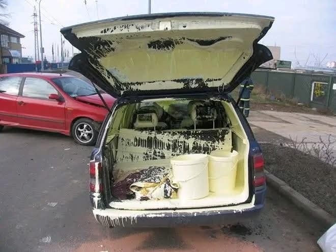 Auto s otvoreným kufrom, v ktorom sú prevrhnuté vedrá s farbou, rozliata po vnútri.