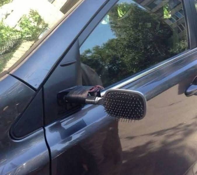 Zrkadlo auta nahradené kefu na vlasy, provizórna oprava, vtipná situácia na parkovisku.