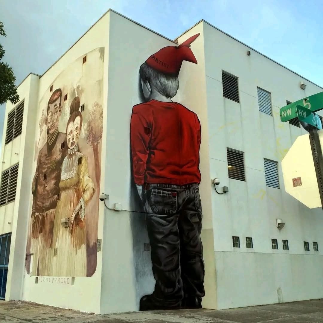 Mural na budove: chlapec v červenom svetríku s opretou hlavou, vedľa staršie portréty s nádychom nostalgie.