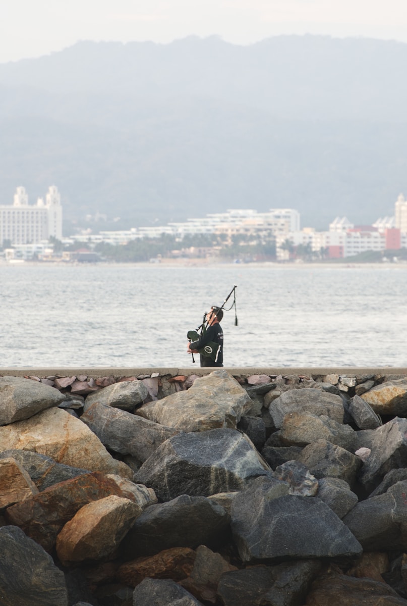 A man holding a fishing pole on top of a rocky beach