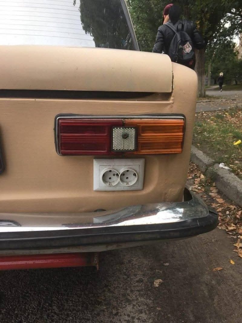 Zadná časť auta s dvojitou elektrickou zásuvkou pod zadným svetlom na neobvyklom mieste.
