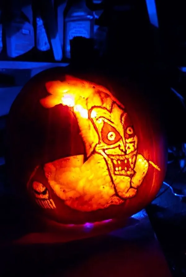 Vyrezávaná tekvica s postavou v temnom osvetlení na Halloween.