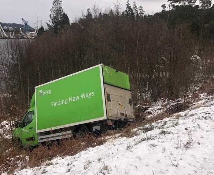 Zelené nákladné auto uviaznuté v zasneženom svahu, slogan Finding New Ways.