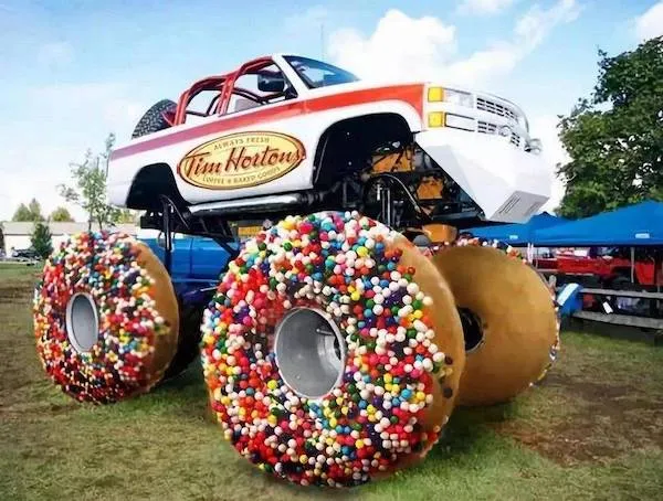 Monster truck s obrovskými kolesami v tvare farebných šišiek na vonkajšej akcii pod modrou oblohou.