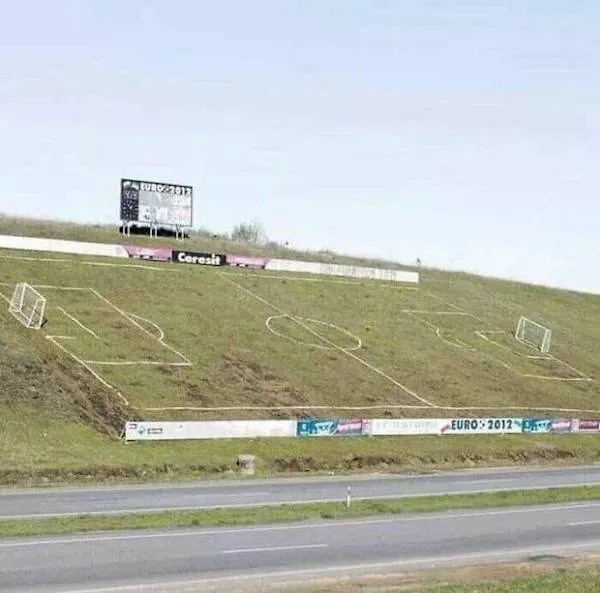 Futbalové ihrisko na svahu vedľa cesty, označené reklamou na EURO 2012.