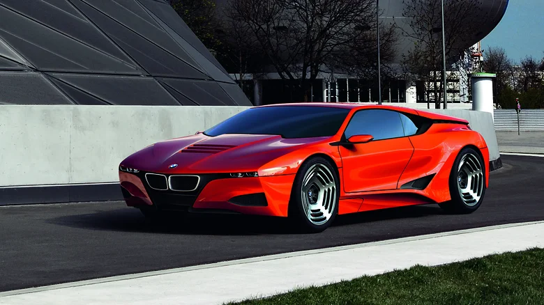 Jasne červené športové auto BMW na ceste, moderný dizajn, slnečný deň, mestské pozadie.