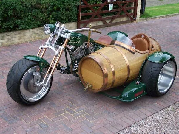 Motorka so sajdkárou v tvare veľkého dreveného suda na dláždenej príjazdovej ceste.