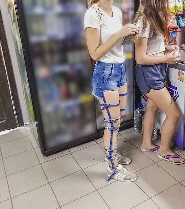 Mladá žena s originálnou modrou páskovou dekoráciou na nohe stojí pri chladničke v obchode.
