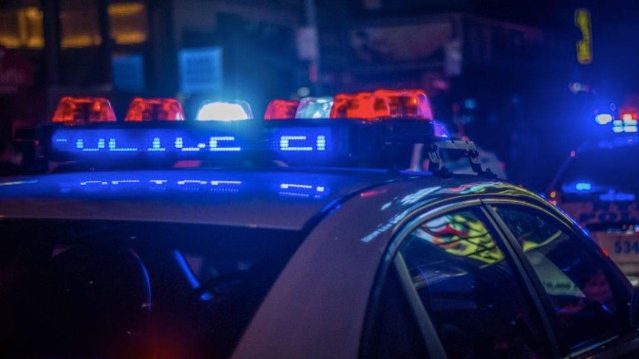 Policajné auto s blikajúcimi modro-červenými majákmi počas nočnej služby v meste.
