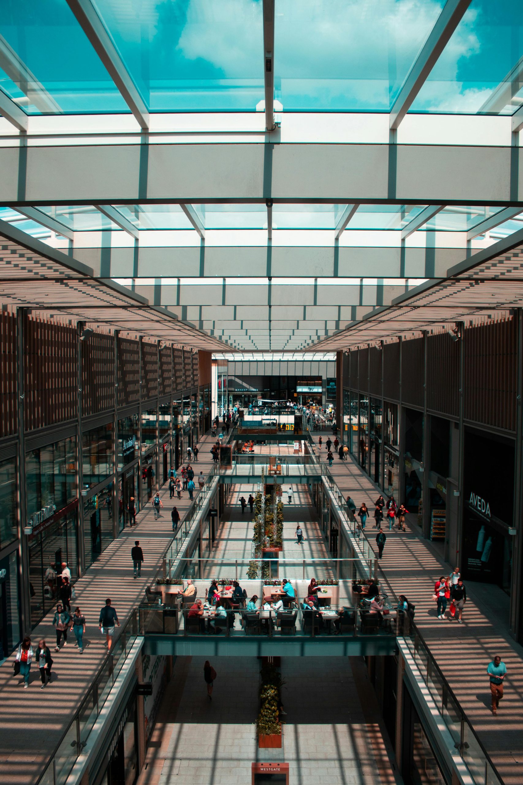 Obchodné centrum s presklenou strechou a chodcami na poschodiach, moderný interiér s obchodmi a kaviarňami.