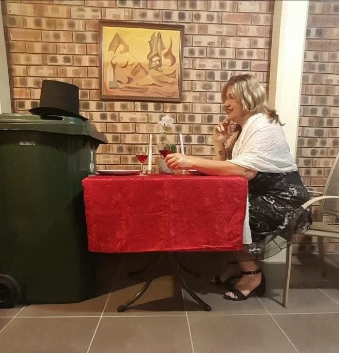 Žena sedí pri stole so sviečkou vedľa odpadkového koša.