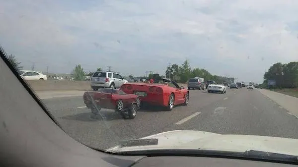 Červené športové auto na diaľnici ťahá malý detský kočík, zaujímavý pohľad na originálny príves.