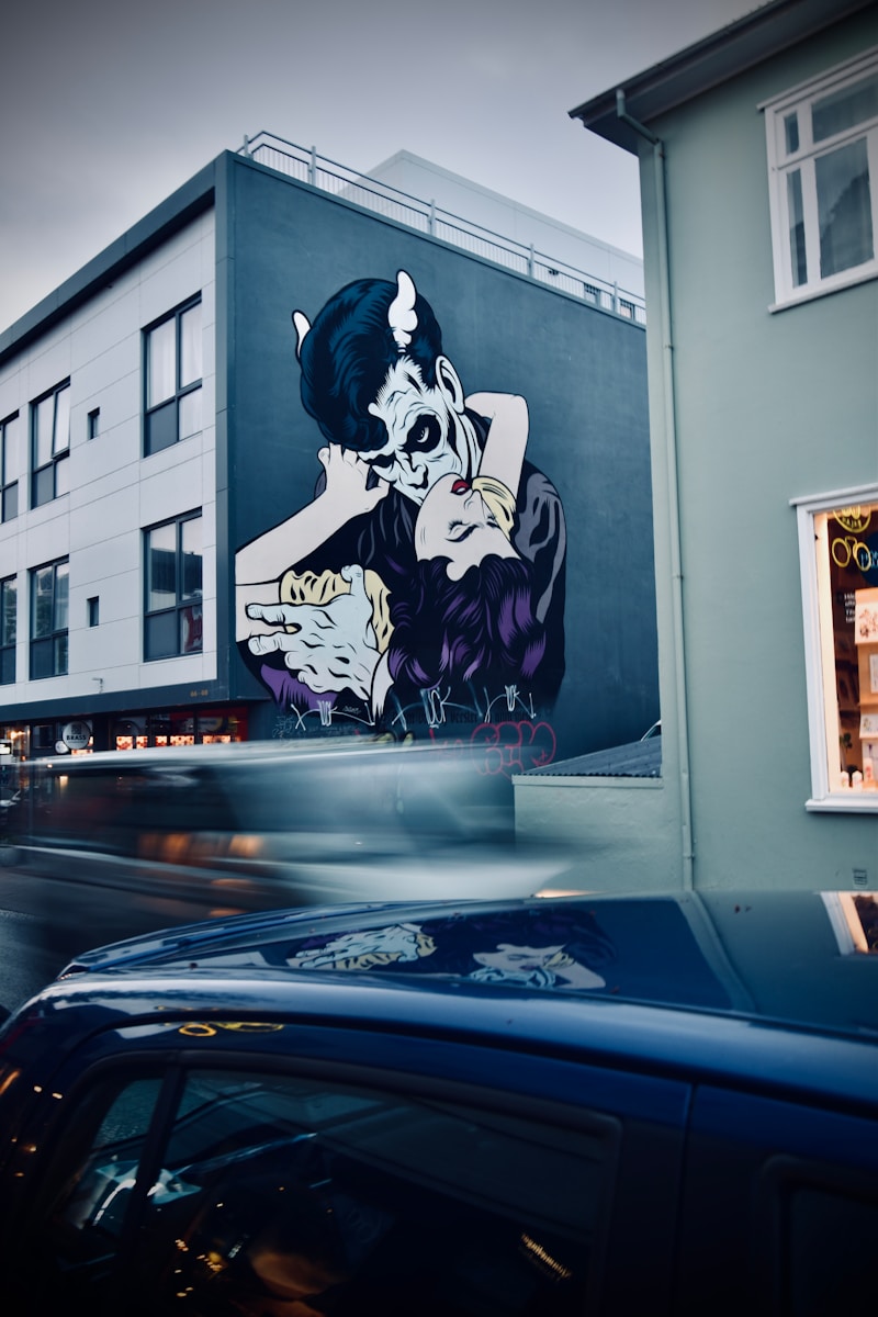 a car driving past a building with a painting on it