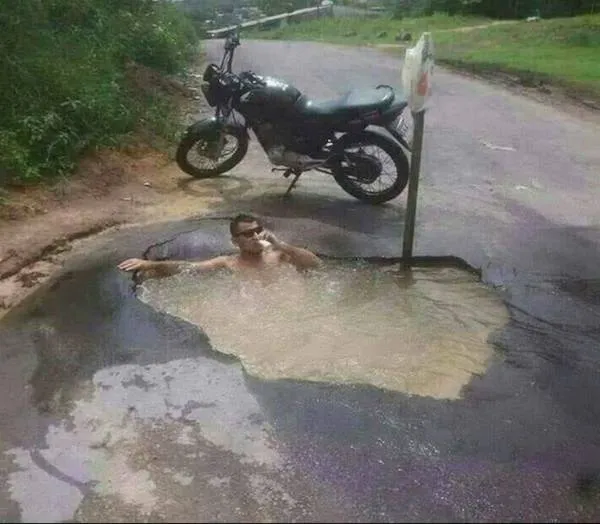 Motorka pri ceste, muž relaxuje vo veľkej mláke, originálne využitie výtlku.