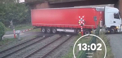 Nákladné auto uviazlo na železničnom priecestí pod mostom, blokované rampami, čas na obrázku je 13:02.