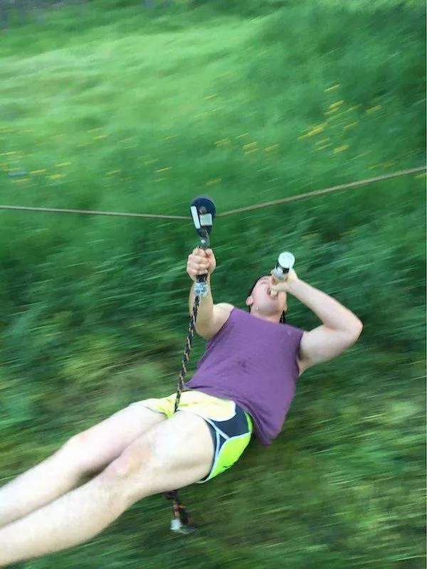 Osoba na lane so zipsom pijúca nápoj, užíva si adrenalínový zážitok v prírode.