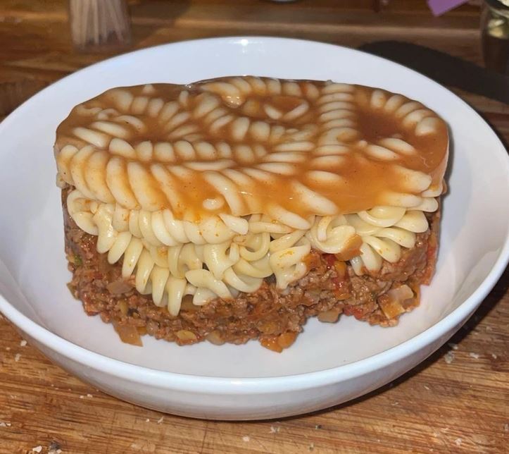 Vrstvené fusilli s omáčkou na mletej mäsovej placke v bielej miske.