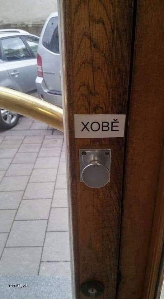 Dvere s nápisom XOBĚ a pohľad na parkovisko vo vonkajšom prostredí.