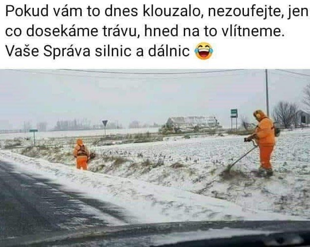 Dva ľudia v oranžových uniformách kosia trávu pri zasneženej ceste v zimnom počasí.