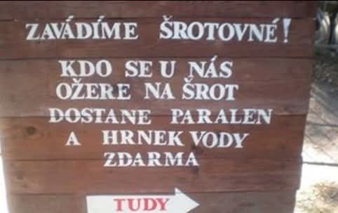 Drevená tabuľa s vtipným nápisom o ponuke nápoja a paralenu zdarma za opitie sa na šrot.