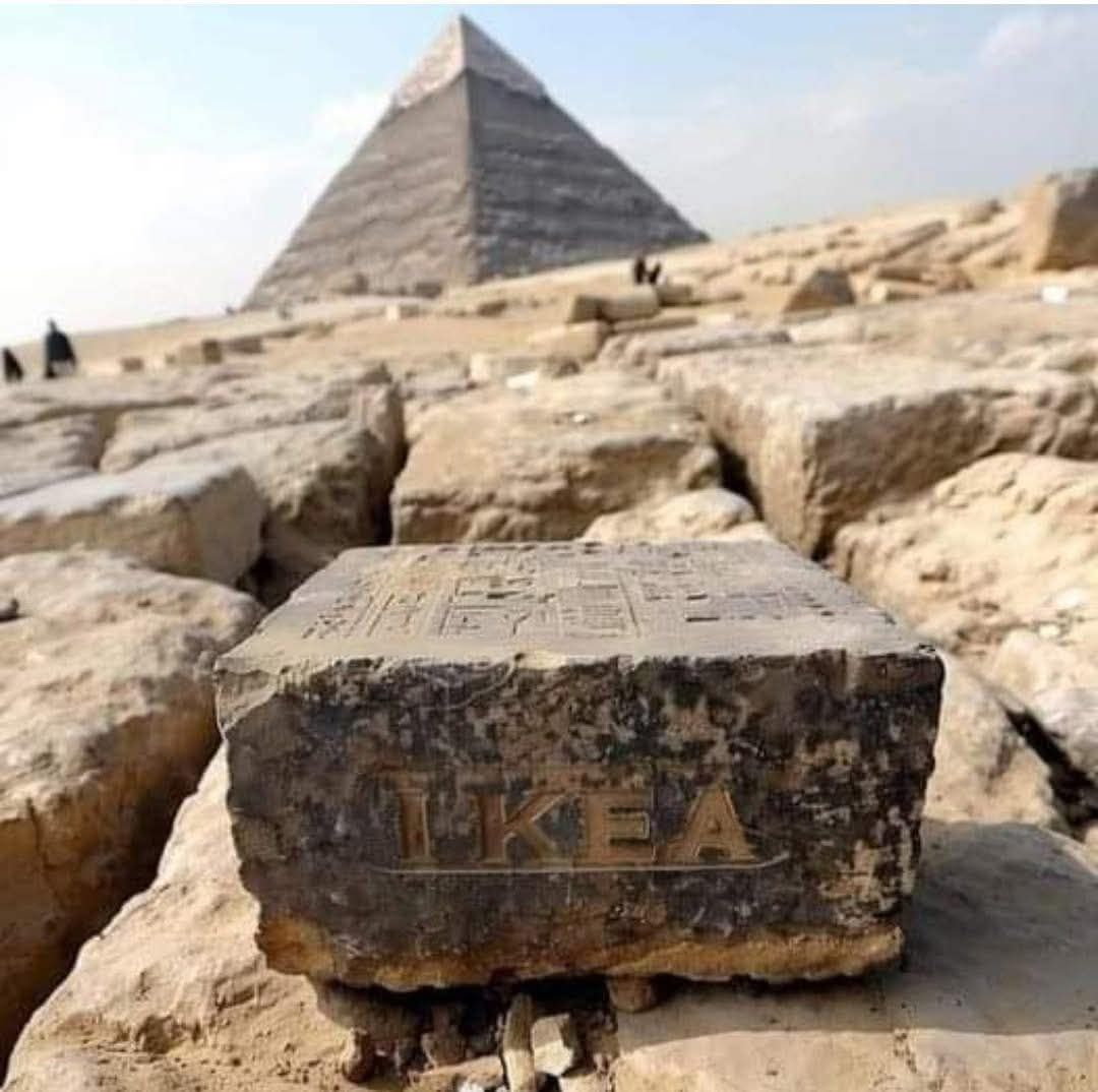 Kamenný blok označený slovom IKEA v popredí pyramídy v Egypte.