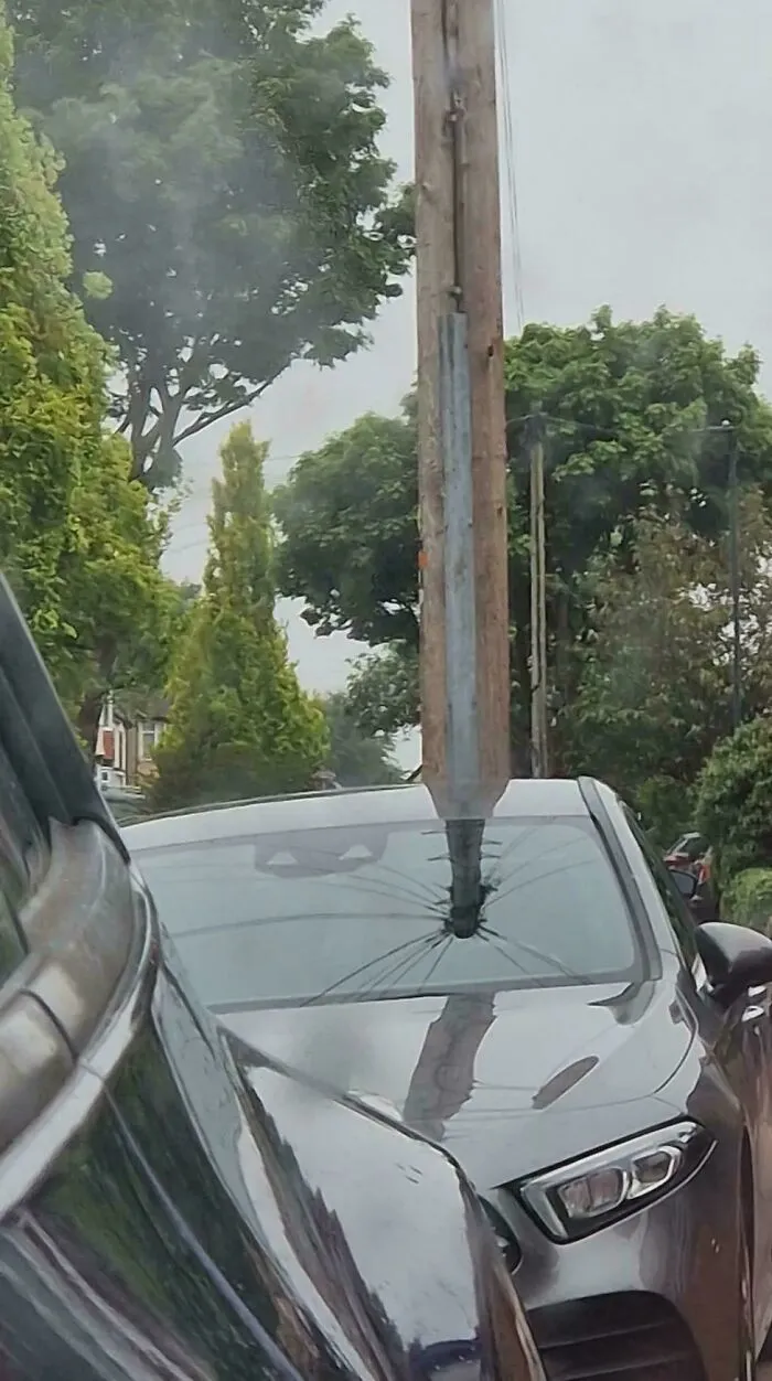 Auto zaparkované pred stĺpom, ktorý vytvára optickú ilúziu, akoby prechádzal cez sklo.