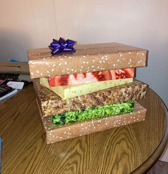 Krabice s hamburgerovým dizajnom na stole, zabalená ako darček s mašľou.