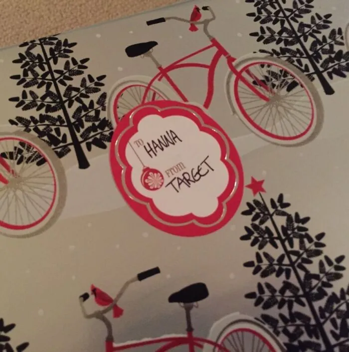 Baliaci papier s bicyklami a nápisom pre Hannah z Target, červeno-čierny vzor s motívom zimných stromov.
