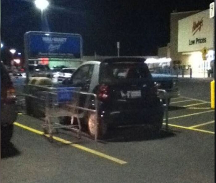 Malé auto zaparkované na parkovacom mieste pre nákupné košíky v supermarkete večer.