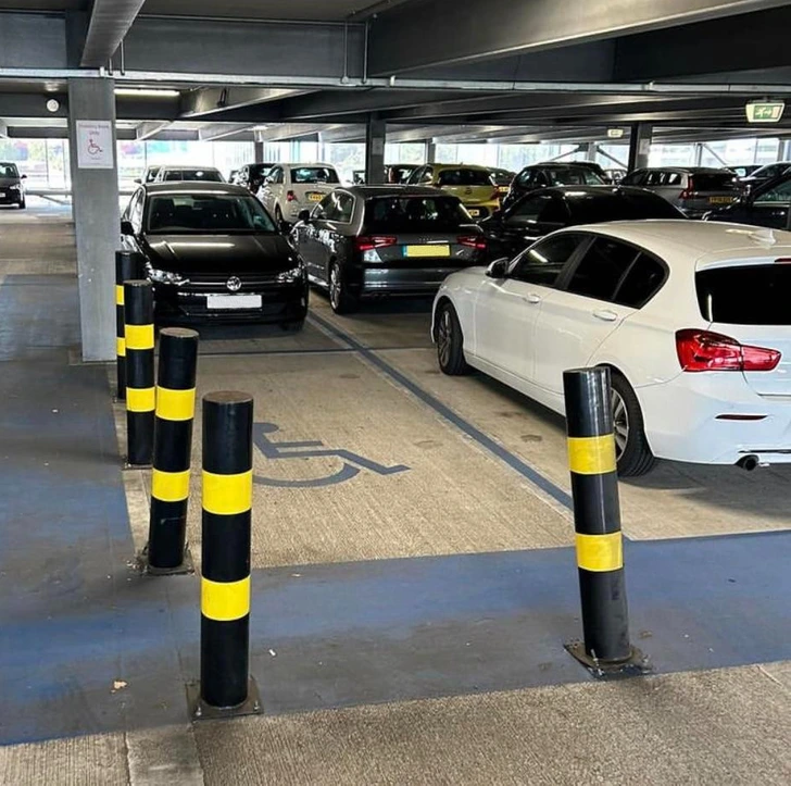 Parkovacie miesto pre invalidov blokované stĺpikmi v podzemnej garáži.