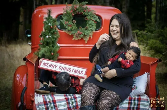 Rodinná vianočná fotografia na korbe červeného auta s vencom, matka s deťmi v objatí a nápisom Merry Christmas.