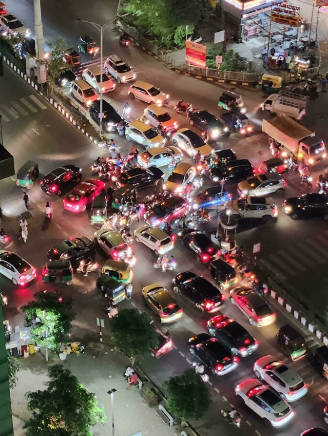 Nočná dopravná zápcha v meste: chaos a preťaženie ciest plné áut a motoriek.