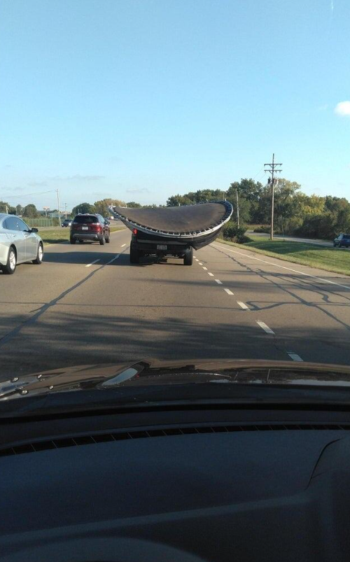 Auto prevážajúce trampolínu na otvorenej ceste počas jasného dňa.