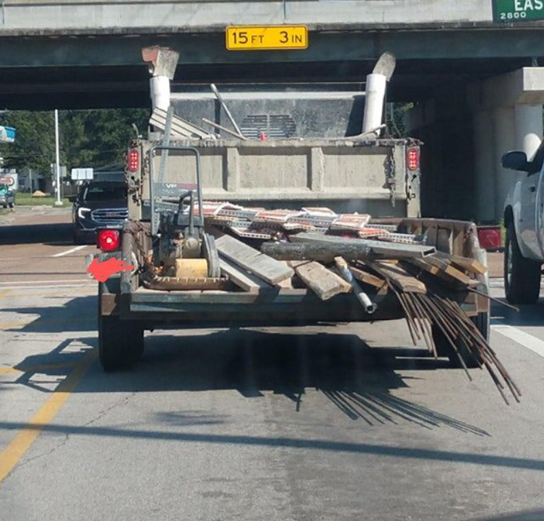 Nákladné auto s otvorenou korbou prepravujúce stavebný materiál a nástroje pod most s výškovým obmedzením.