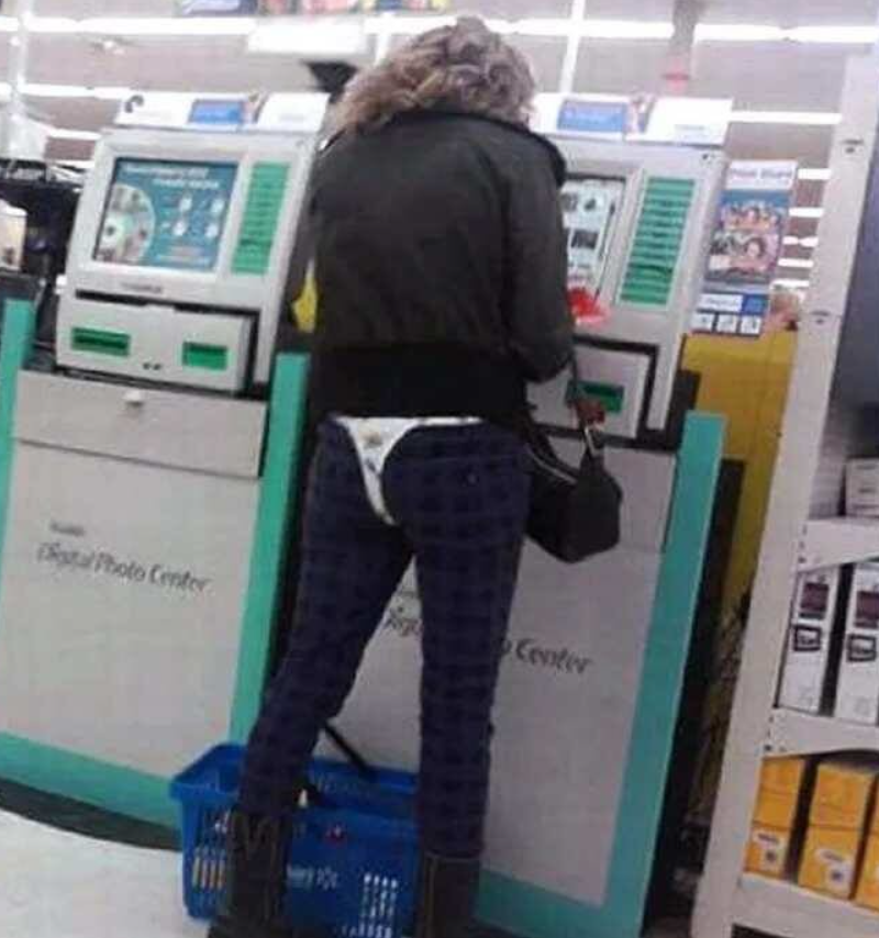 Žena v obchode pri kiosku s digitálnymi produktmi, kôš na nákupy na podlahe.