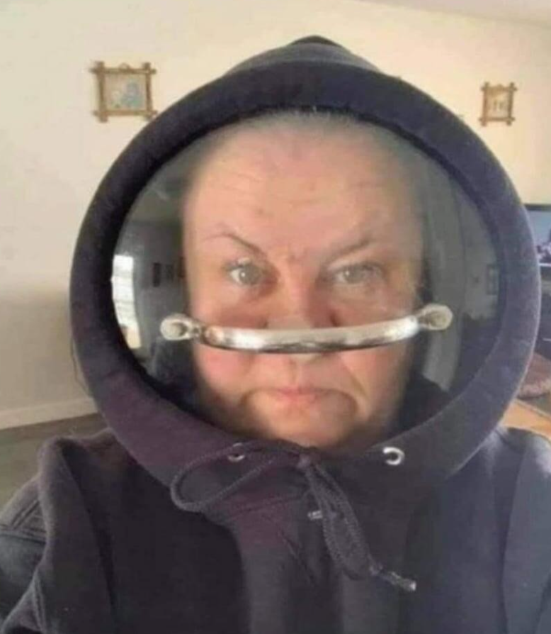 Osoba s kapucňou a zväčšovacím sklom pred tvárou, vytvára humoristický efekt na vzhľad.