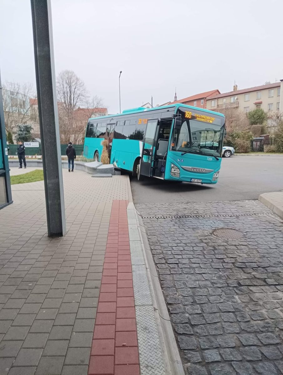 Autobus na zastávke v meste, časť predku mimo krajnice, ľudia nastupujúci a vystupujúci.