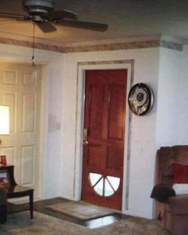 Interiérový dizajn s drevenými dverami s netradičným oknom, ventilátorom na stropě a pohodlnou obývačkou.