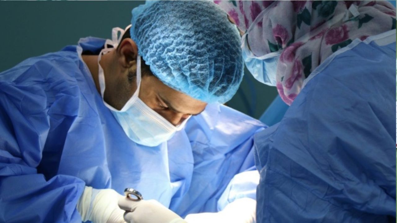 Chirurgický tím pracujúci v operačnej sále, chirurg sústredene vykonáva zákrok.