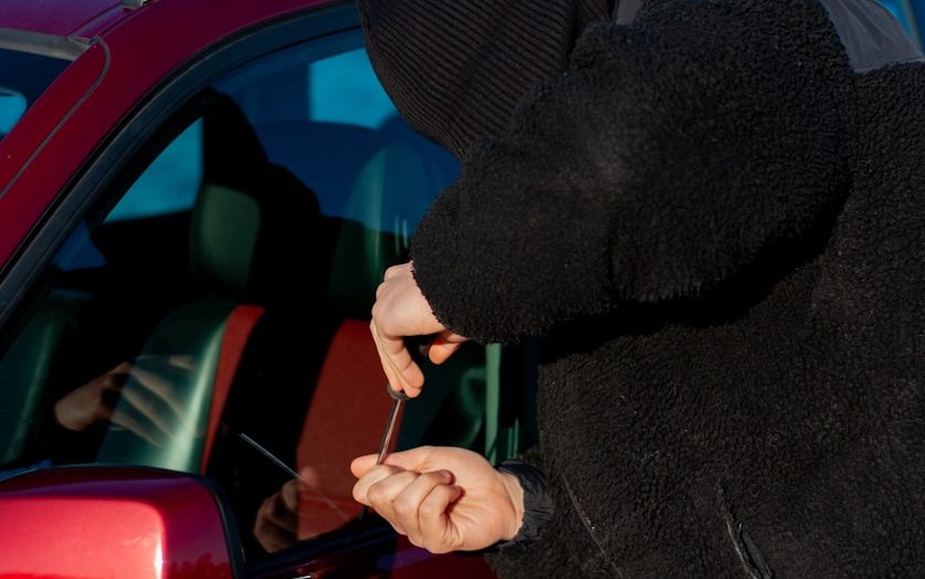 A thief is trying to break into a car.