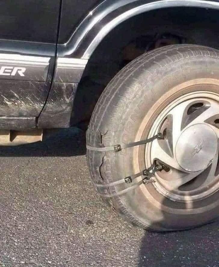 Auto s poškodenou pneumatikou zaistenou plastovými páskami, viditeľné praskliny a provizórne opravené koleso.