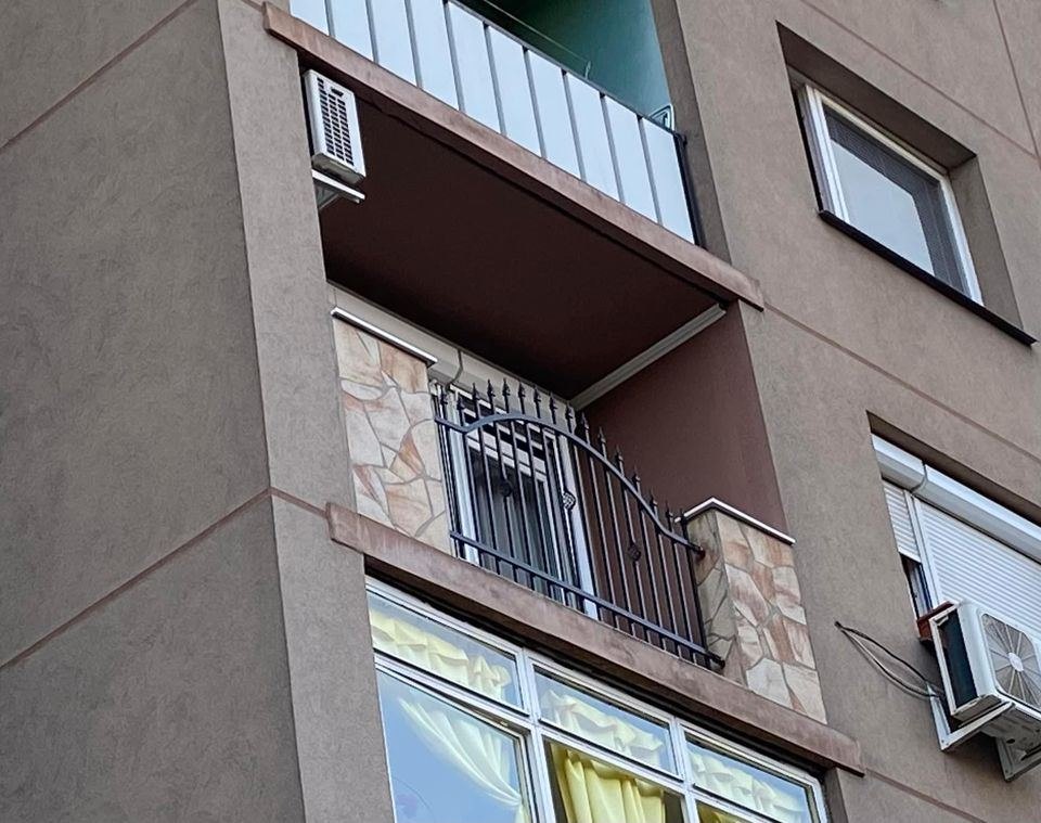 Balkón na bytovke s mriežkovým zábradlím a klimatizáciou na stene.