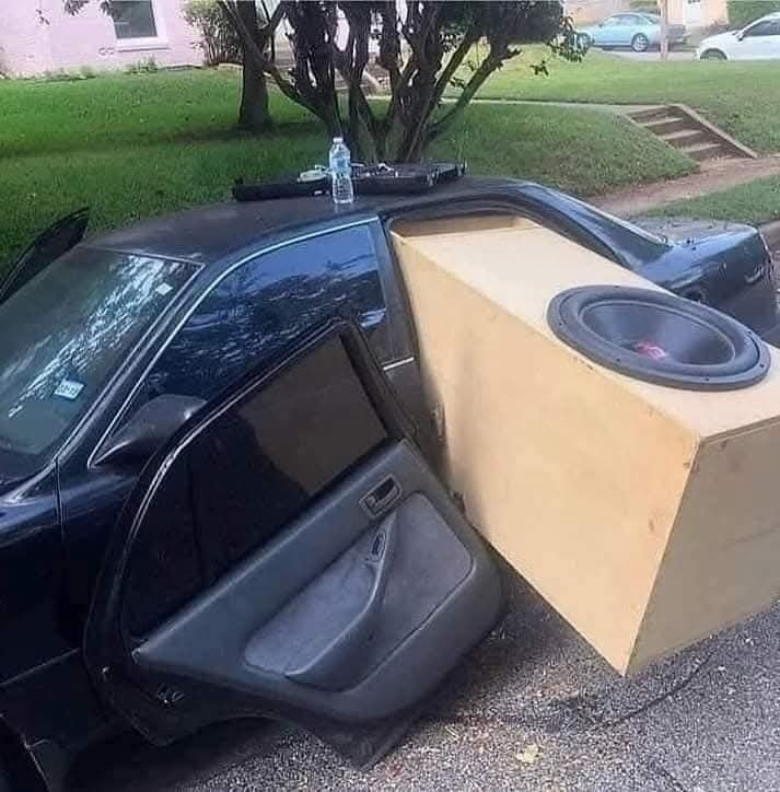Auto s obrovským subwooferom presahujúcim cez zadné dvere na parkovisku.