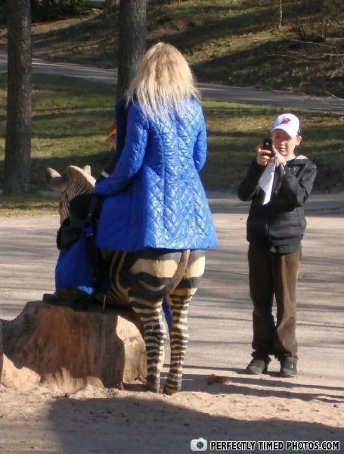 Žena v modrej bunde sediaca na lavičke s nápadne zebrovitým vzorom, chlapec ju fotí.
