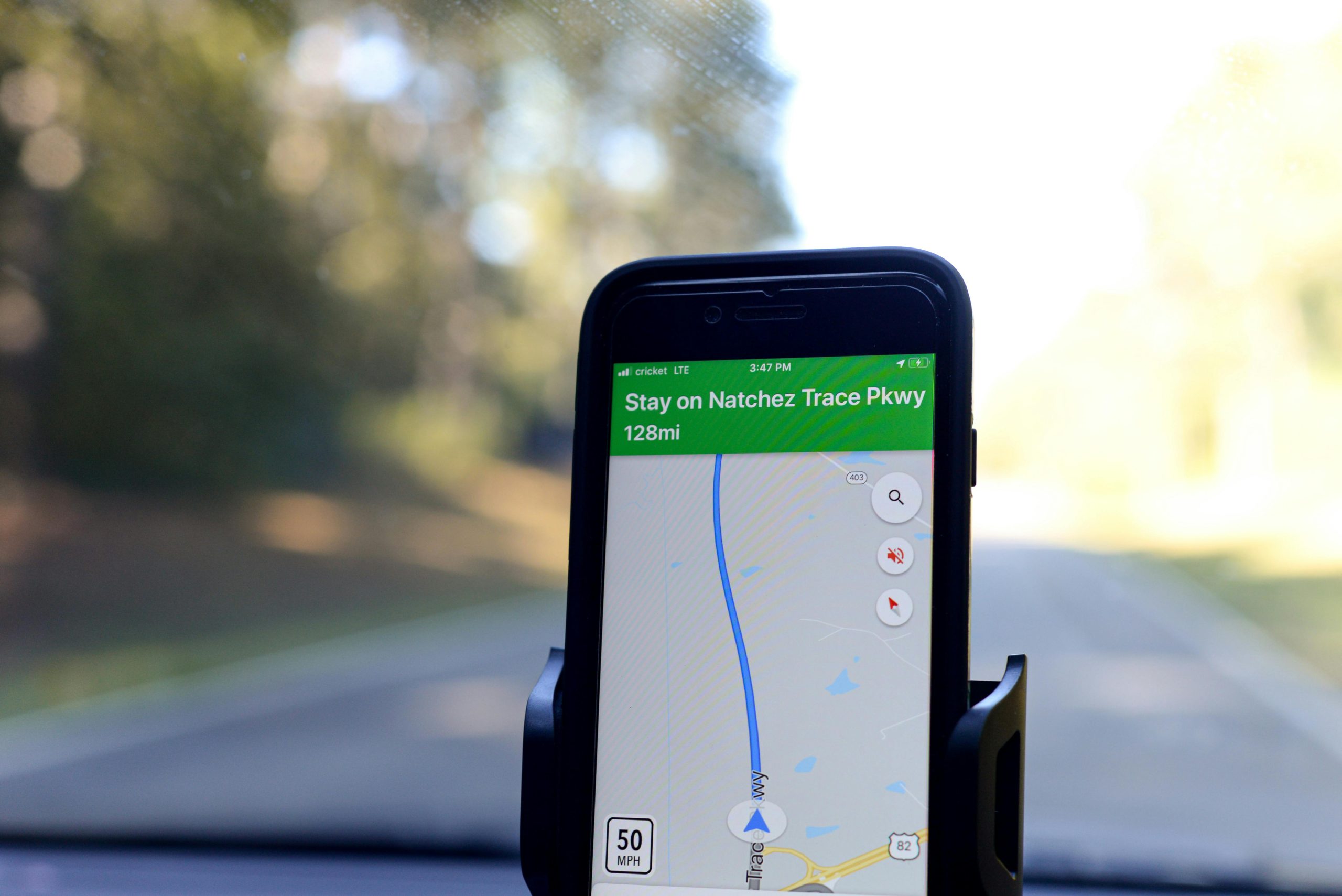 Navigácia na telefóne ukazuje trasu po Natchez Trace Parkway, vzdialenosť 128 míľ, rýchlosť 50 MPH.