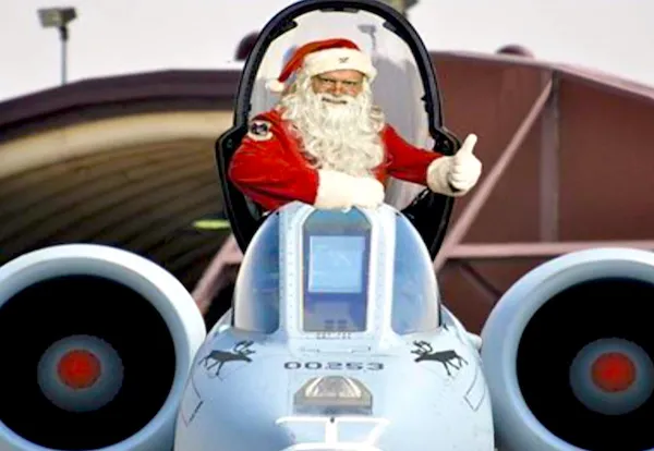 Santa v kokpite lietadla, ukazujúci palec hore, pripravený na sviatočnú misiu namiesto saní.