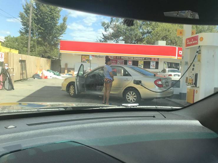 Žena tankuje auto na čerpacej stanici v letný deň.