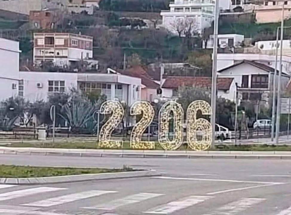Osvetlené číslo 2206 na kruhovom objazde s pozadím mestských budov a vegetácie.