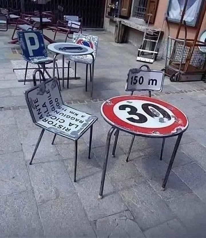 Stolík a stoličky vyrobené z dopravných značiek na terase kaviarne.