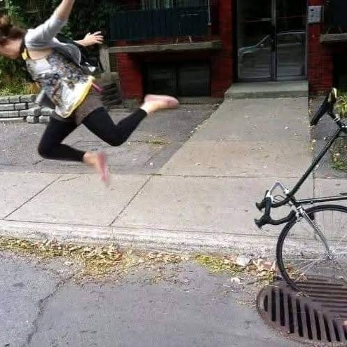 Osoba skáče z obrubníka na bicykel zaparkovaný pri obrubníku na ulici.
